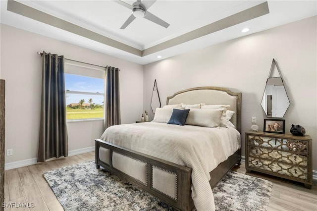 bedroom featuring a tray ceiling, ceiling fan, and light wood-type flooring