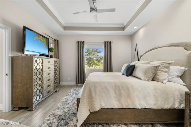 bedroom with a tray ceiling, light hardwood / wood-style flooring, and ornamental molding