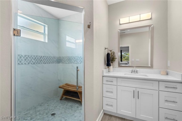 bathroom with a tile shower and vanity