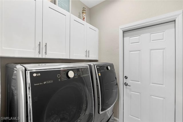 clothes washing area with cabinets and washer and dryer