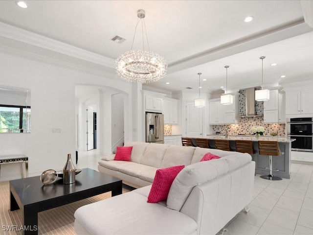 living room with sink, crown molding, and a chandelier