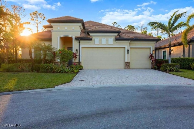 mediterranean / spanish home with a garage and a front lawn