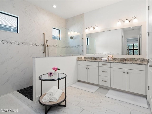 bathroom featuring a tile shower, vanity, and a wealth of natural light