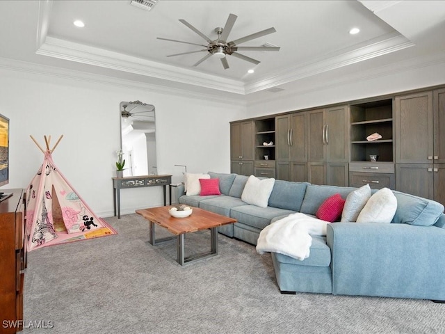 living room with ceiling fan, light colored carpet, ornamental molding, and a raised ceiling