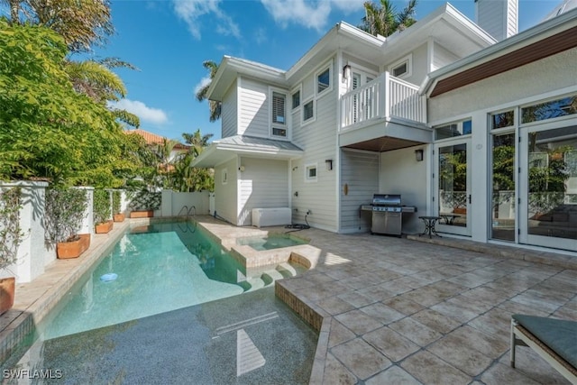 rear view of property featuring a patio area and a pool with hot tub