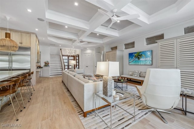 living room with coffered ceiling, crown molding, light wood-type flooring, beamed ceiling, and ceiling fan with notable chandelier