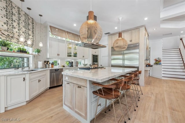 kitchen featuring stainless steel appliances, light stone countertops, hanging light fixtures, and a center island