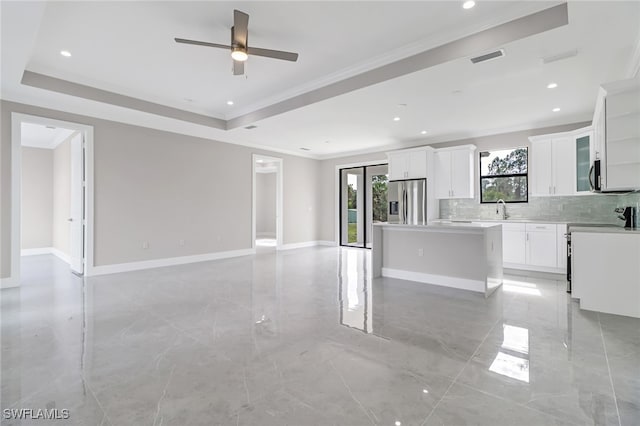 kitchen featuring white cabinetry, stainless steel fridge, a raised ceiling, and a kitchen island