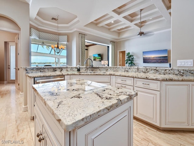 kitchen featuring light stone counters, sink, coffered ceiling, and a center island