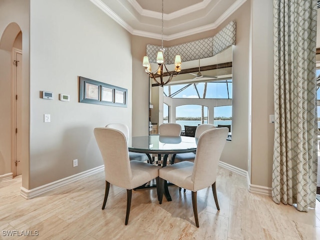 dining space featuring a high ceiling, a notable chandelier, light hardwood / wood-style floors, a raised ceiling, and crown molding