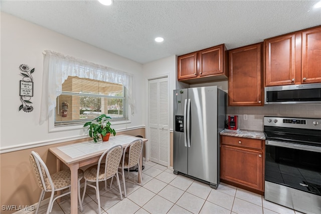 kitchen featuring light tile patterned floors, decorative backsplash, stainless steel appliances, a textured ceiling, and light countertops