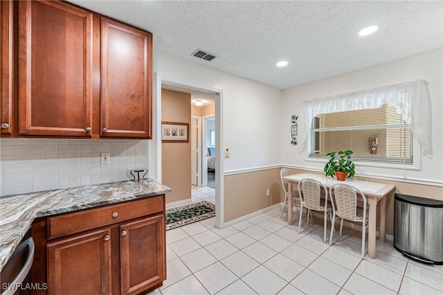 kitchen featuring visible vents, backsplash, light stone counters, and light tile patterned flooring