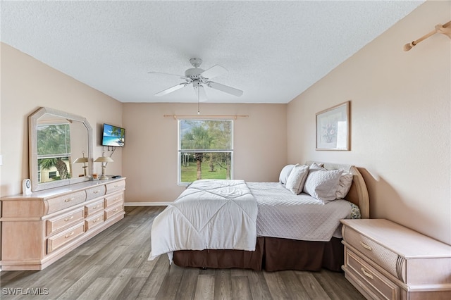 bedroom featuring light wood-style flooring, a ceiling fan, and a textured ceiling