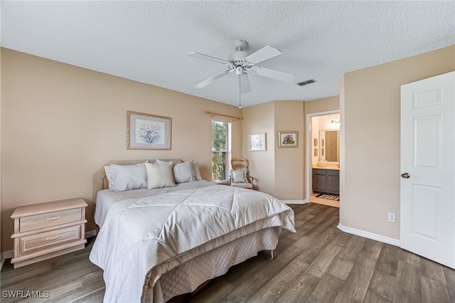 bedroom featuring dark wood finished floors, visible vents, connected bathroom, a textured ceiling, and baseboards