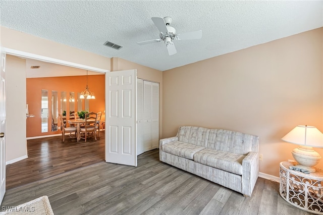 sitting room with visible vents, a textured ceiling, baseboards, and wood finished floors