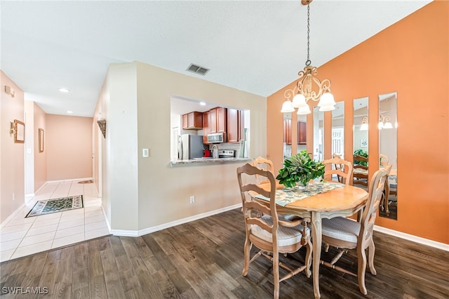 dining area featuring baseboards, visible vents, wood finished floors, vaulted ceiling, and a chandelier