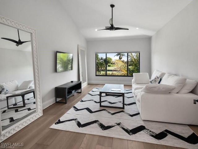 living room with dark wood-type flooring, ceiling fan, and vaulted ceiling