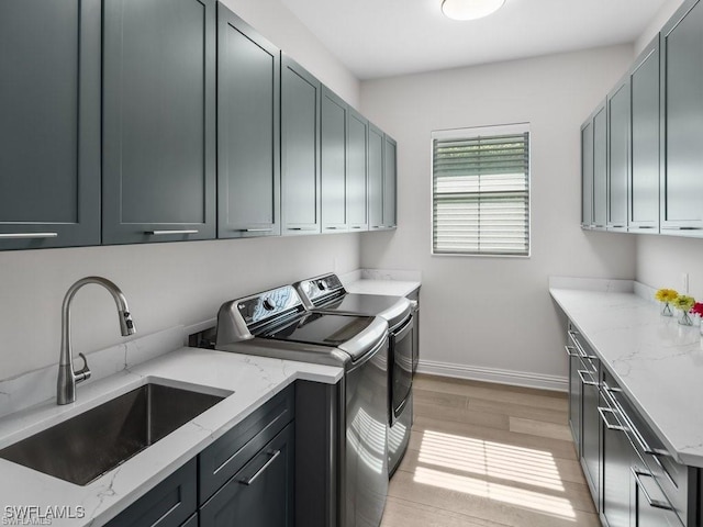 laundry room with light hardwood / wood-style floors, cabinets, washer and clothes dryer, and sink