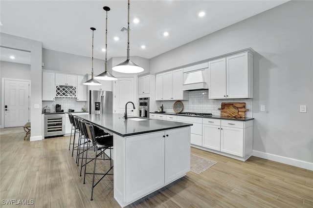 kitchen featuring pendant lighting, white cabinetry, sink, custom exhaust hood, and stainless steel appliances