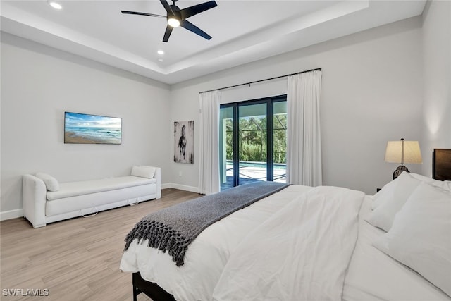 bedroom with ceiling fan, a raised ceiling, light wood-type flooring, and access to outside