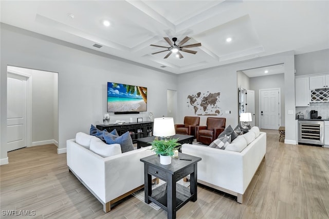 living room with beamed ceiling, coffered ceiling, wine cooler, and light wood-type flooring