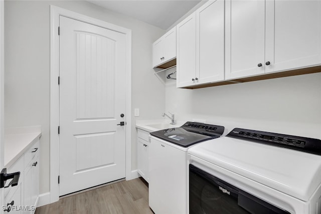 laundry area with separate washer and dryer, sink, cabinets, and light wood-type flooring