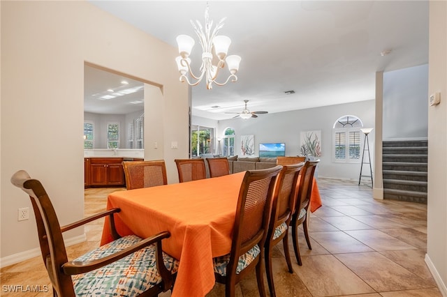 dining space with ceiling fan with notable chandelier, a wealth of natural light, and light tile patterned flooring