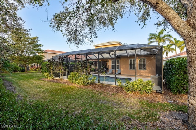 rear view of house featuring a lanai, a lawn, and a patio area