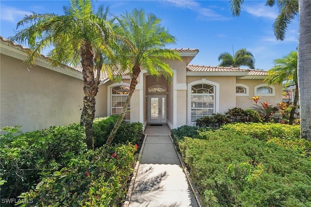 entrance to property featuring a tiled roof and stucco siding