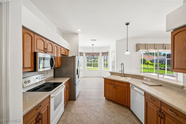 kitchen featuring brown cabinets, stainless steel appliances, a sink, and light countertops