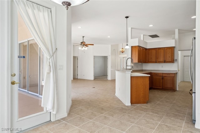 kitchen with brown cabinets, light countertops, open floor plan, ceiling fan, and a peninsula