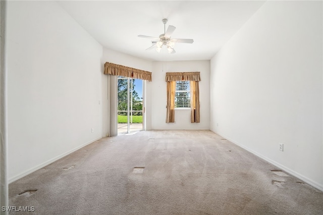 empty room with carpet, a ceiling fan, and baseboards