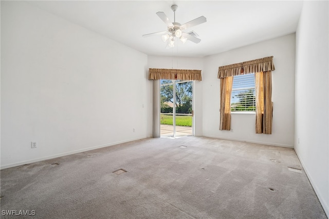 carpeted empty room featuring baseboards and a ceiling fan