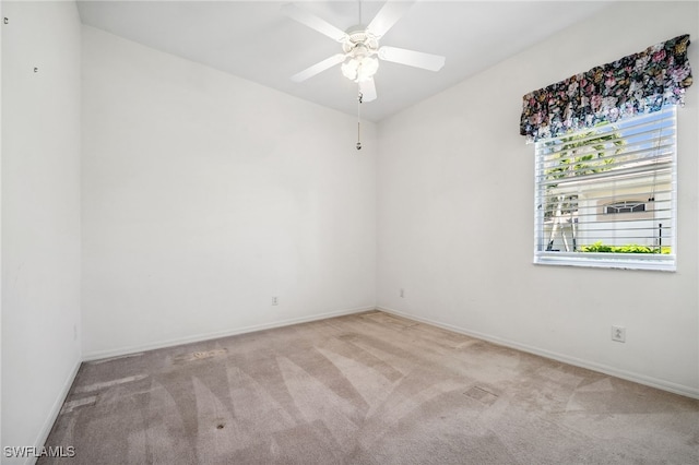 carpeted empty room with a ceiling fan and baseboards