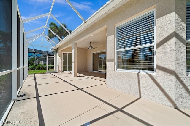 exterior space featuring glass enclosure and ceiling fan