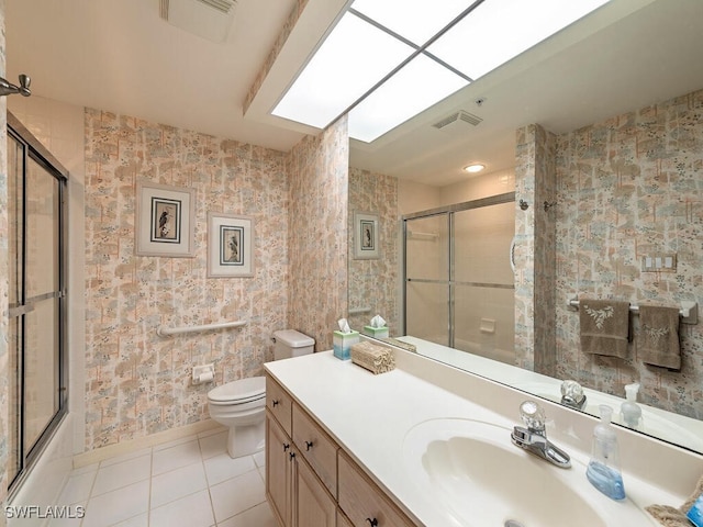 full bathroom with vanity, bath / shower combo with glass door, tile patterned floors, and toilet