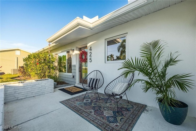 entrance to property with a patio area, central AC, and stucco siding