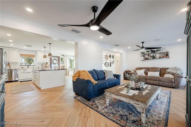 living room with crown molding, ceiling fan, light parquet flooring, and sink