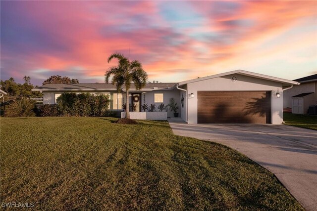 ranch-style home with a garage and a lawn