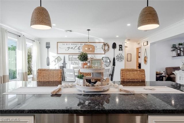 kitchen featuring pendant lighting, crown molding, and dark stone countertops