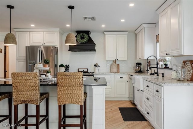 kitchen featuring white cabinetry, stainless steel fridge, and light stone countertops