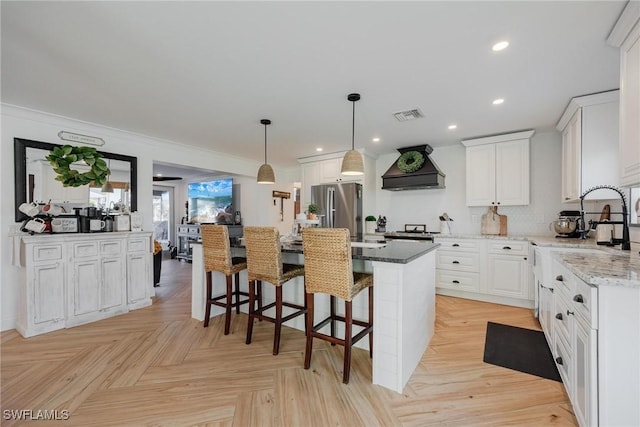 kitchen with custom exhaust hood, white cabinetry, light stone counters, a kitchen island, and light parquet floors