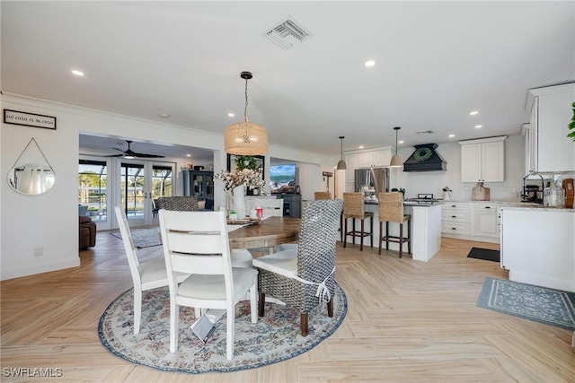 dining space featuring ceiling fan, crown molding, sink, and light parquet flooring