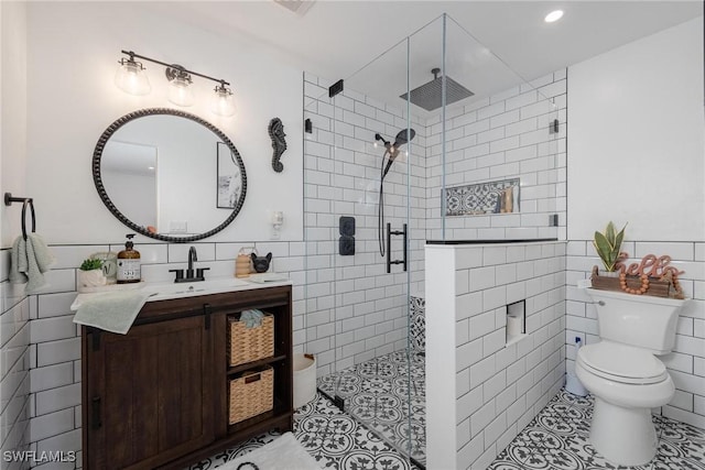 bathroom with toilet, an enclosed shower, tile walls, vanity, and tile patterned flooring