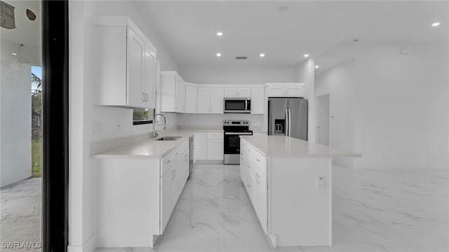 kitchen with white cabinetry, appliances with stainless steel finishes, sink, and a kitchen island