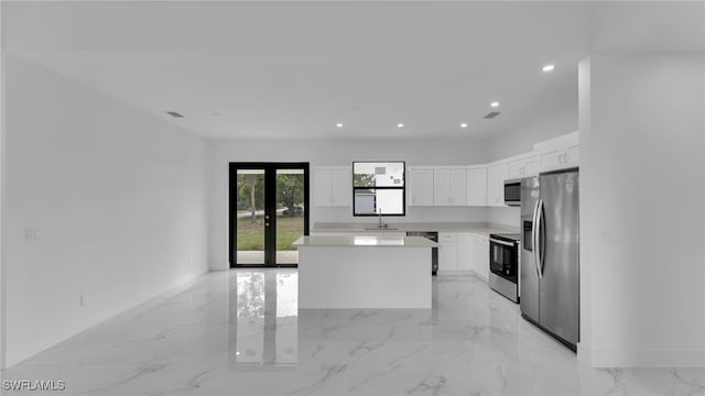 kitchen featuring stainless steel appliances, white cabinetry, a center island, and french doors