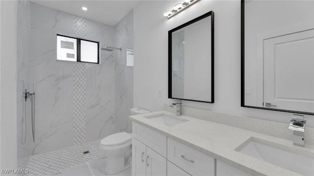 bathroom with vanity, tiled shower, and toilet