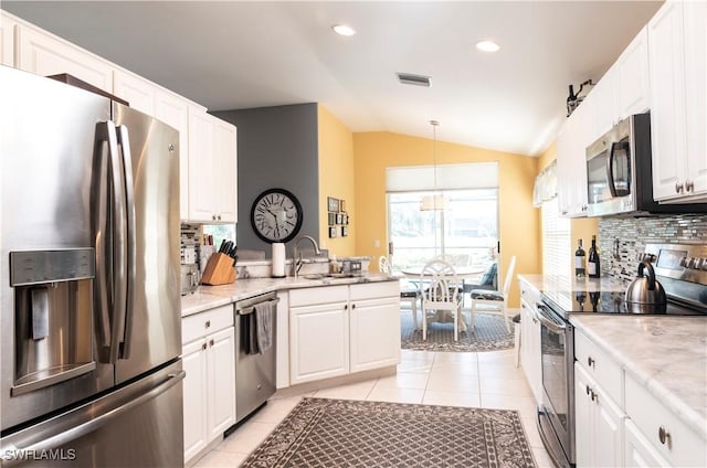 kitchen featuring sink, appliances with stainless steel finishes, white cabinets, light tile patterned flooring, and decorative light fixtures