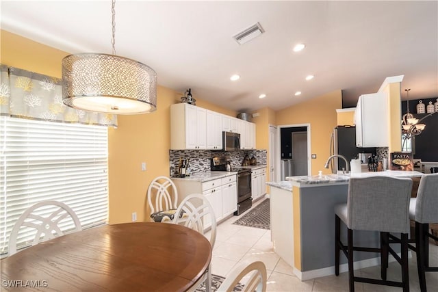 kitchen with light stone counters, tasteful backsplash, appliances with stainless steel finishes, kitchen peninsula, and white cabinets