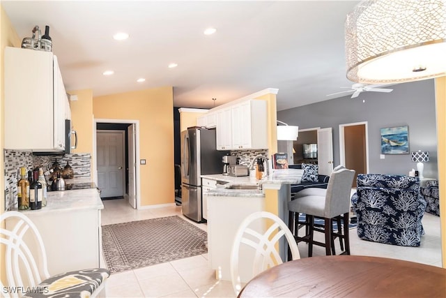 kitchen with white cabinetry, tasteful backsplash, appliances with stainless steel finishes, kitchen peninsula, and light stone countertops